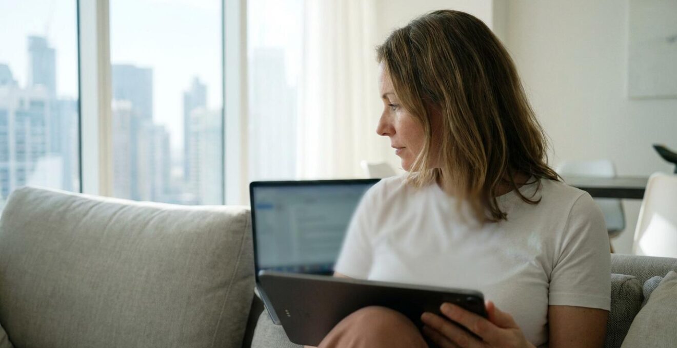 Personne consultant une estimation immobilière sur tablette dans salon moderne suisse